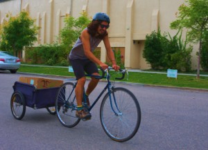 Cyclist pulling trailer of food.