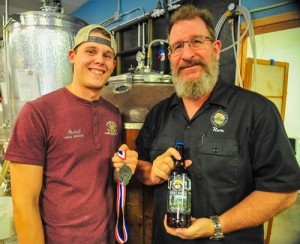 Head brewer Mitchell Nichols, left, holds the silver medal won at this year's Great American Beer Festival for his Piney Ridge Dunkel. Front Range Brewing owner Ron Hoglund (right) holds a bottle of Piney Ridge.