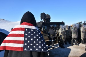 standing rock protester stands before police