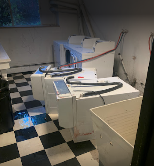 Photo of shared laundry room with two machines turned over and disconnected from the wall. 